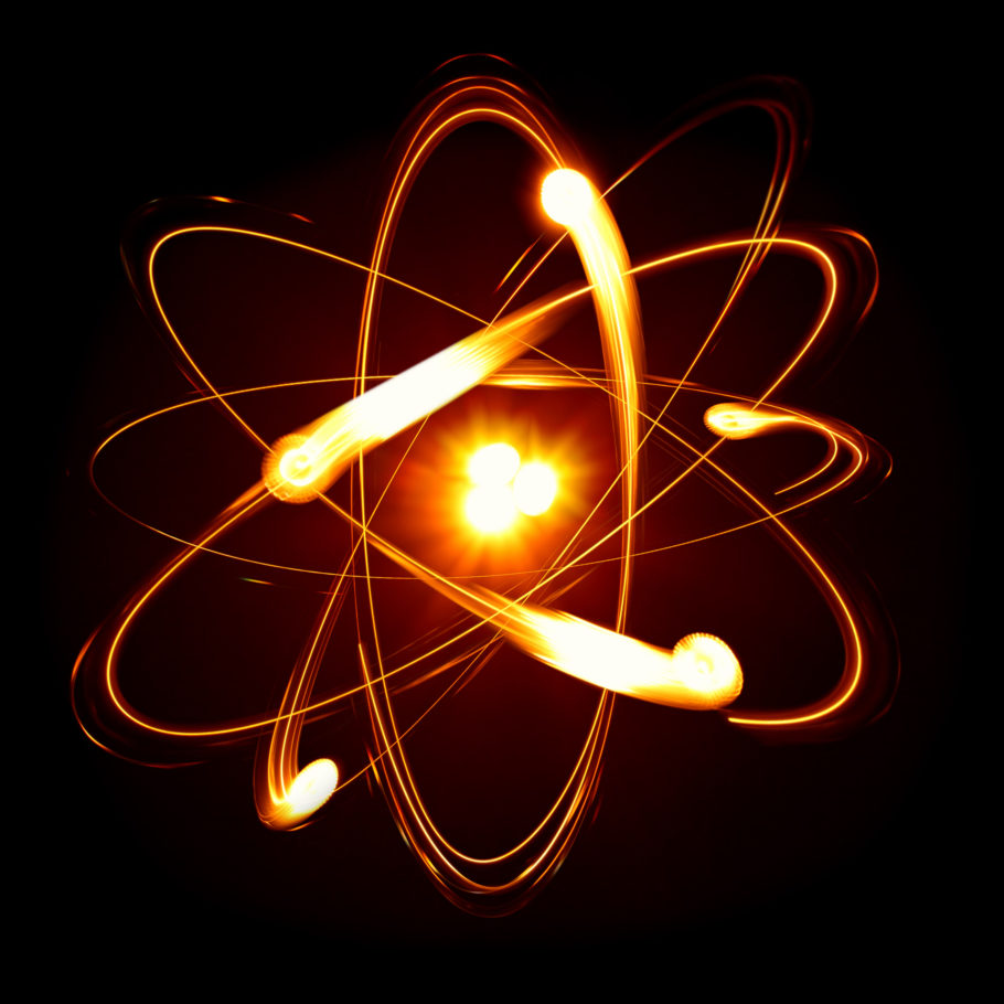 Um átomo desenhado com seu núcleo incandescente e elétrons girando em diferentes planos da eletrosfera.